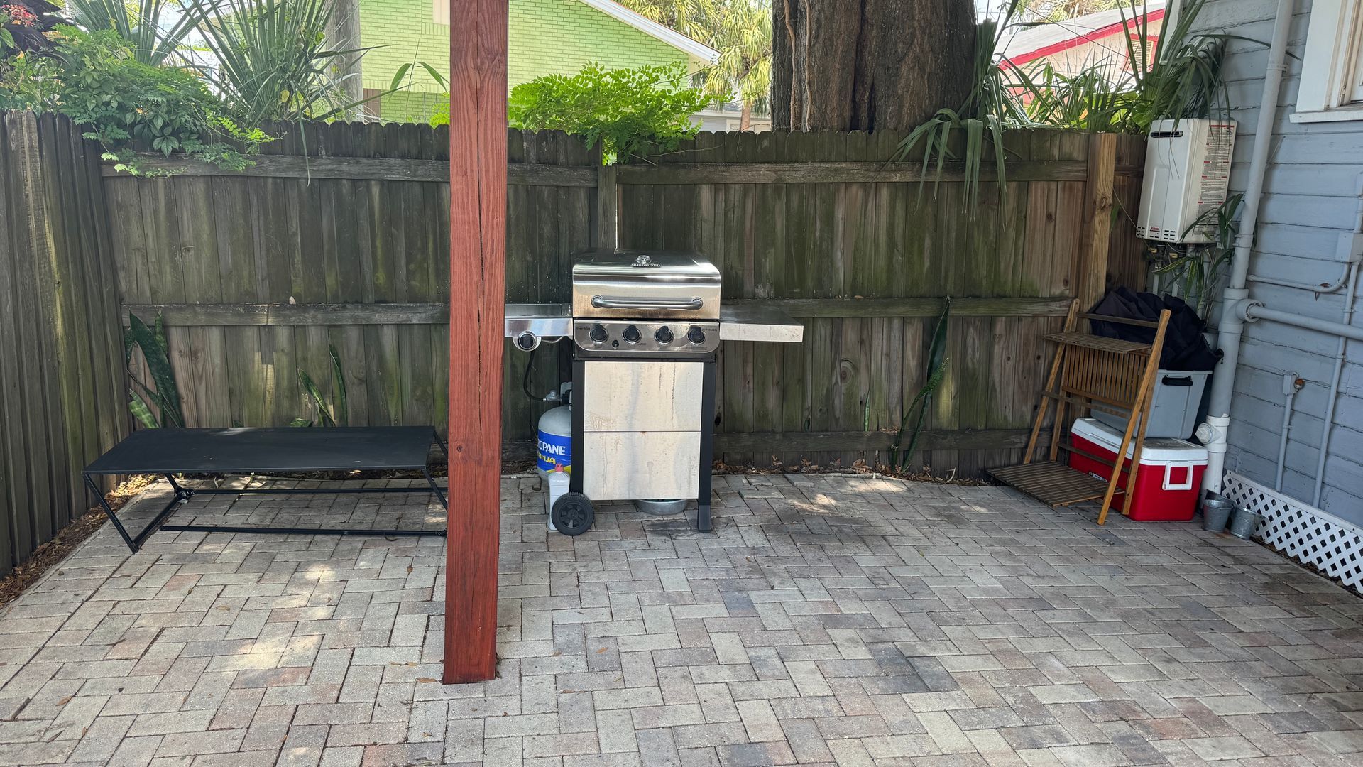 A grill is sitting on a patio next to a wooden fence.