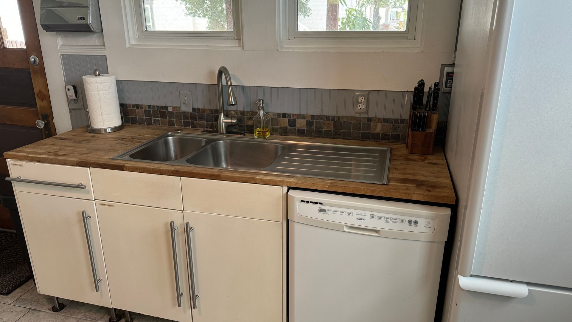 A kitchen with a sink , dishwasher , refrigerator and window.