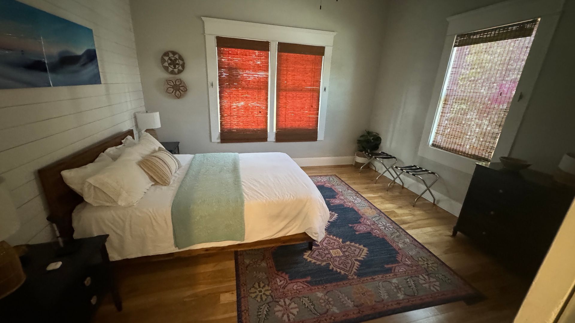 A bedroom with a bed , rug and two windows.