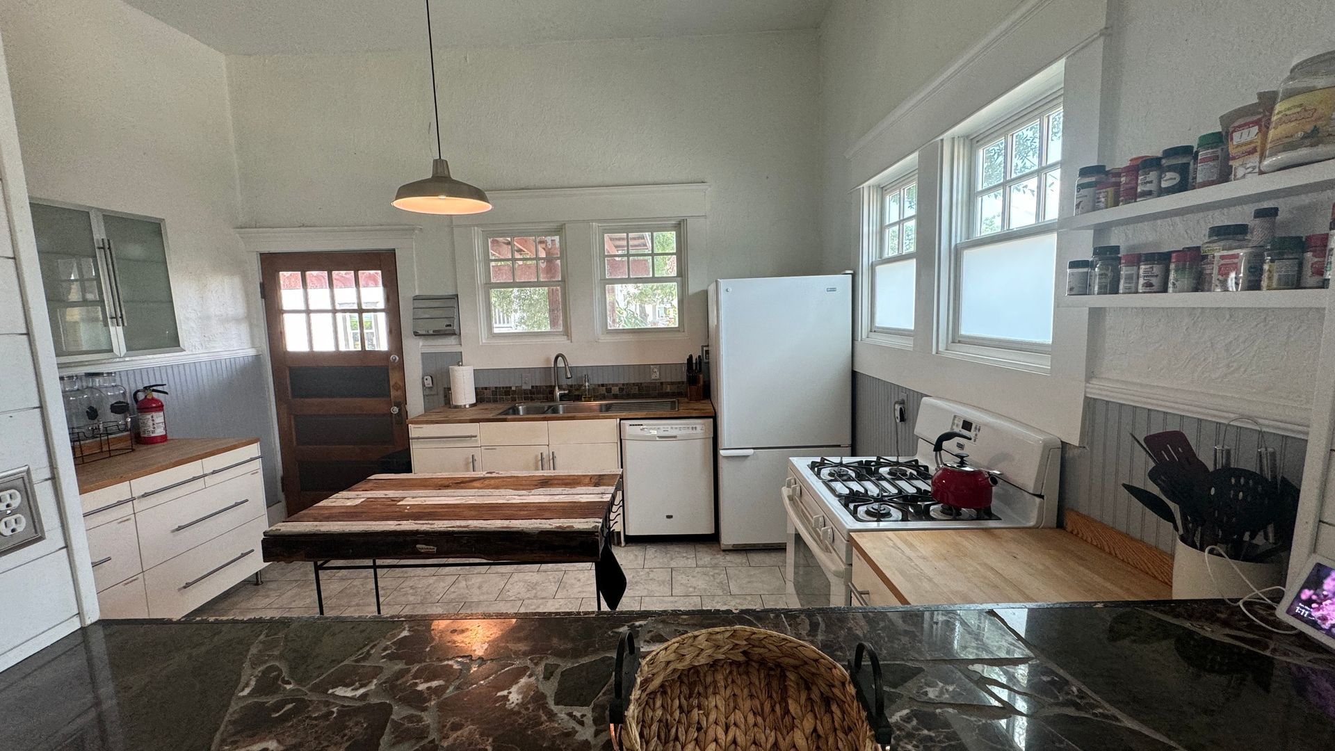 A kitchen with a stove , refrigerator , dishwasher , sink and table.