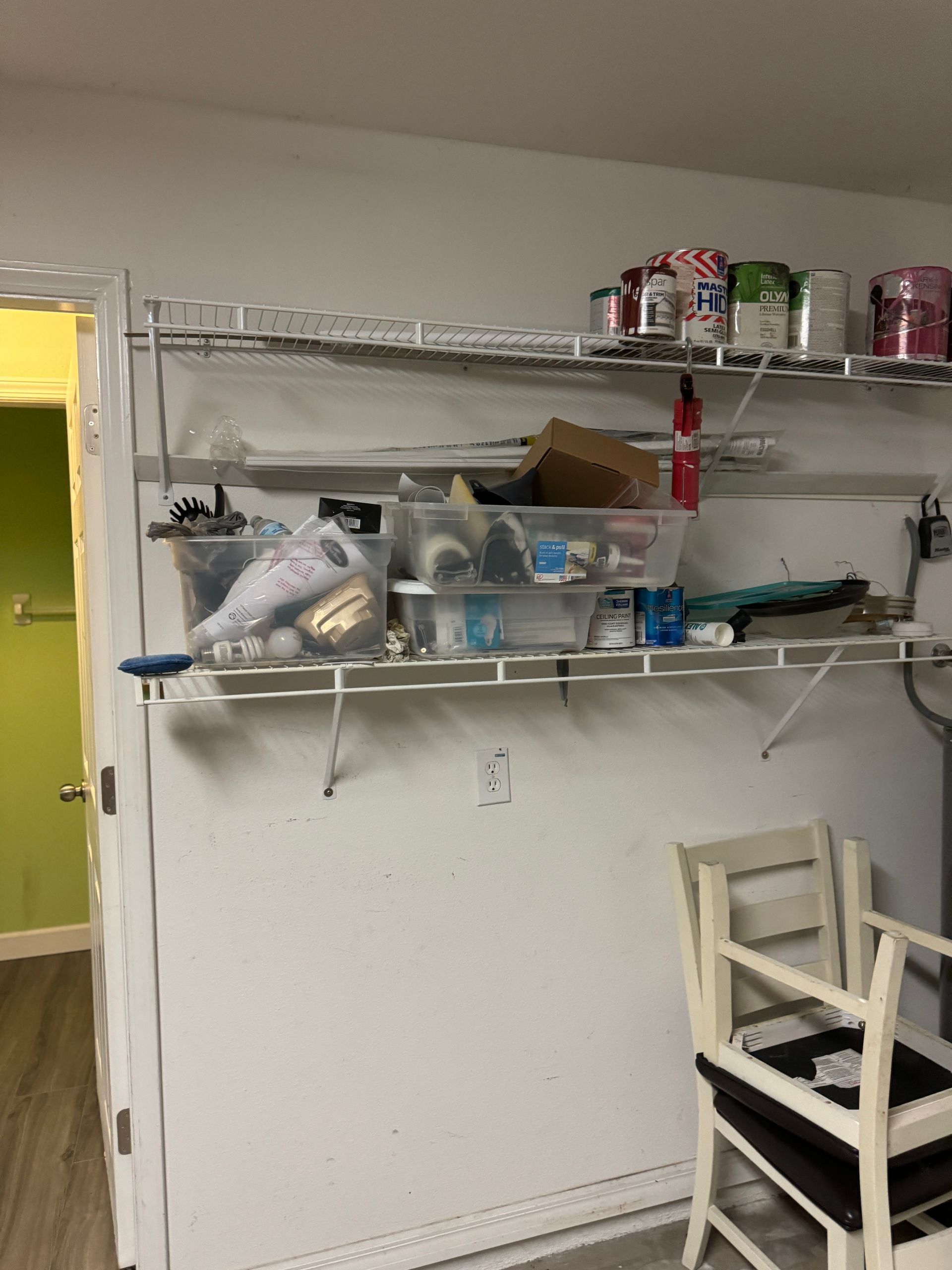 A room with a shelf filled with lots of items and a chair.