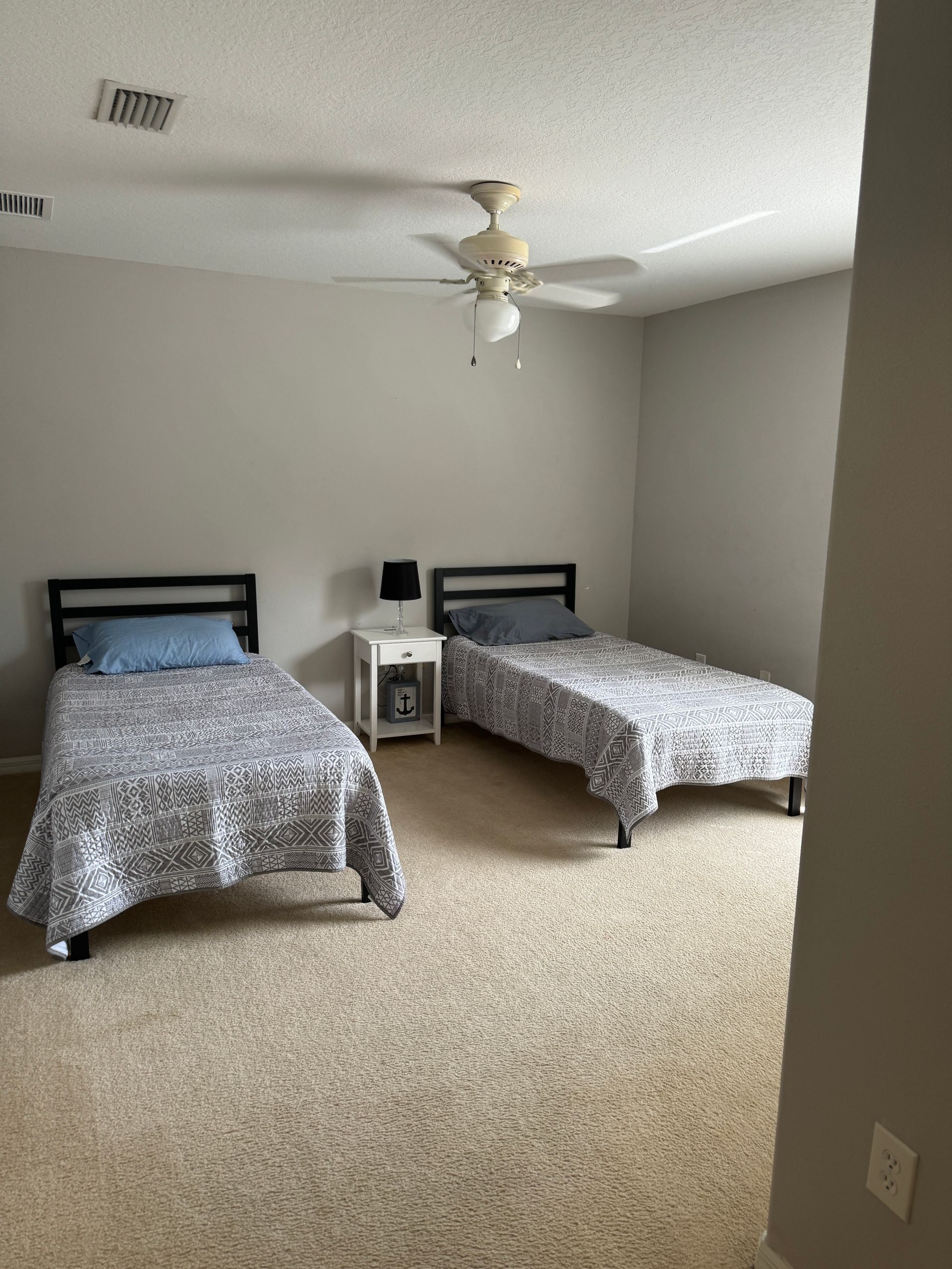A bedroom with two beds and a ceiling fan