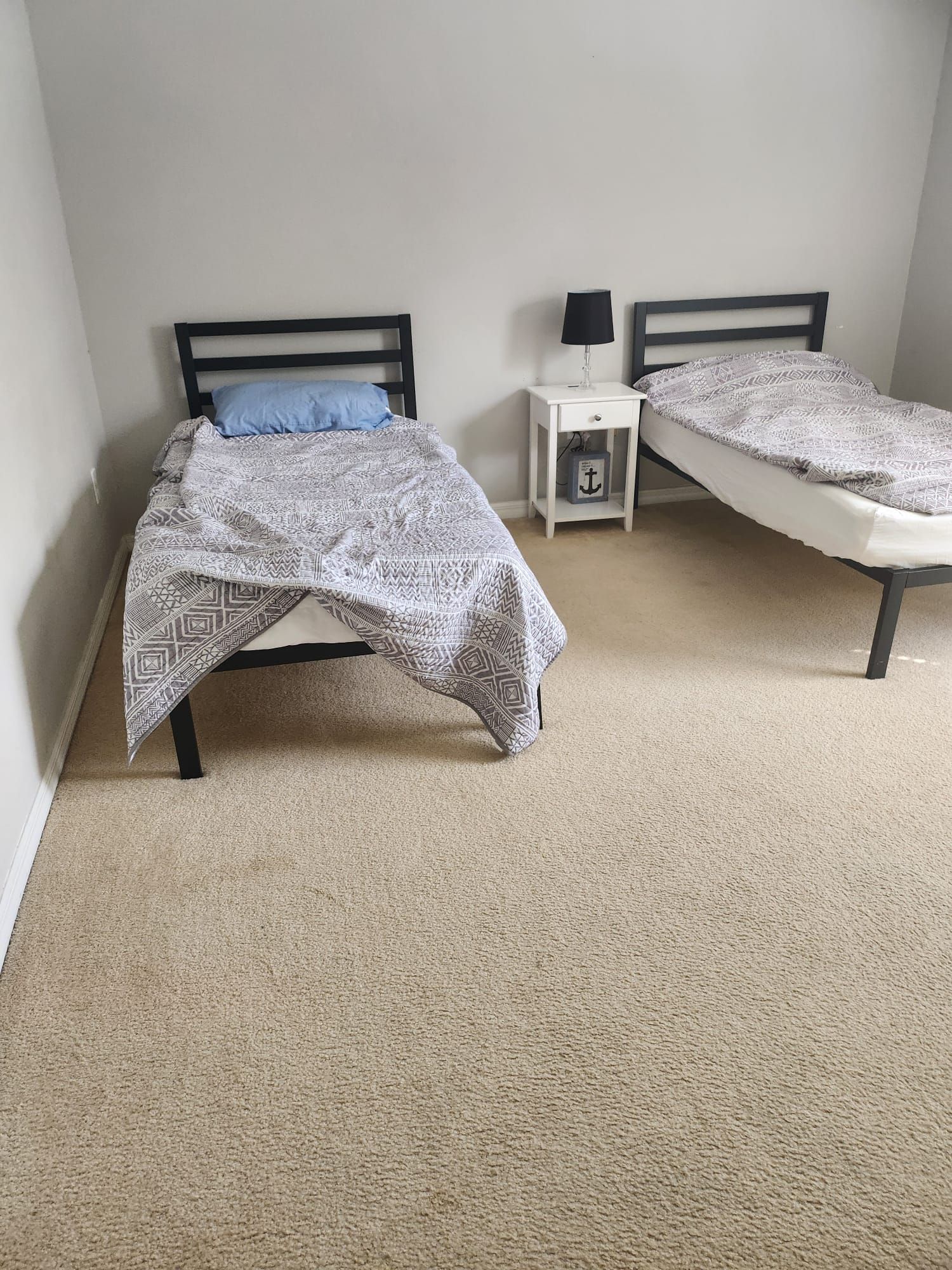 A bedroom with two beds and a nightstand.