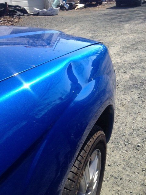 A close up of a blue car 's fender and hood