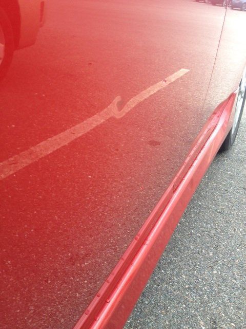A red car is parked on the side of the road.