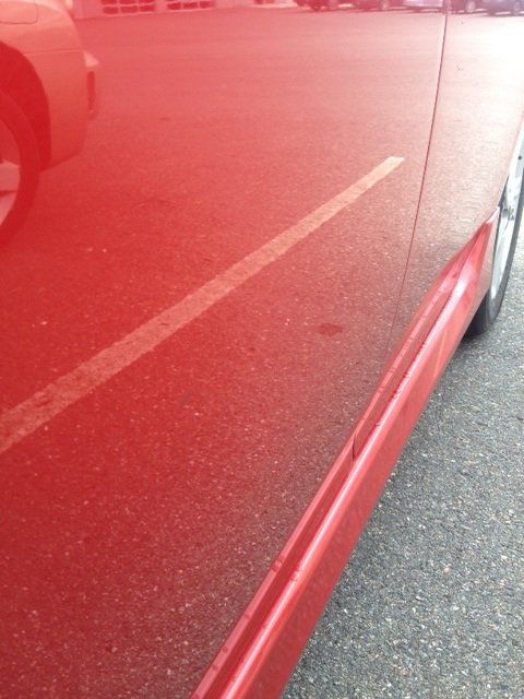 A red car is parked in a parking lot