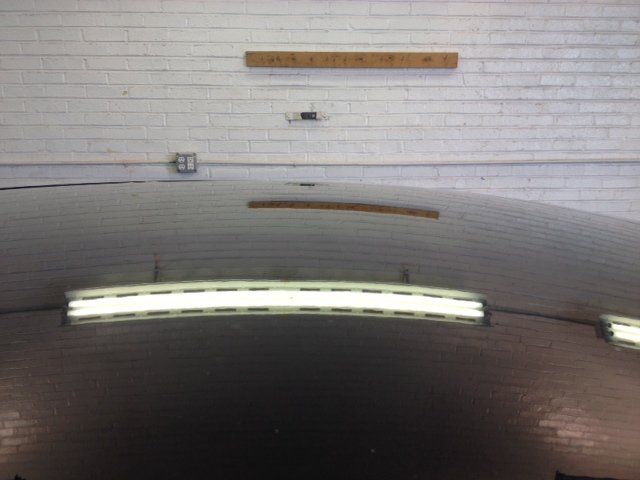 A car is parked in a garage with a white brick wall.