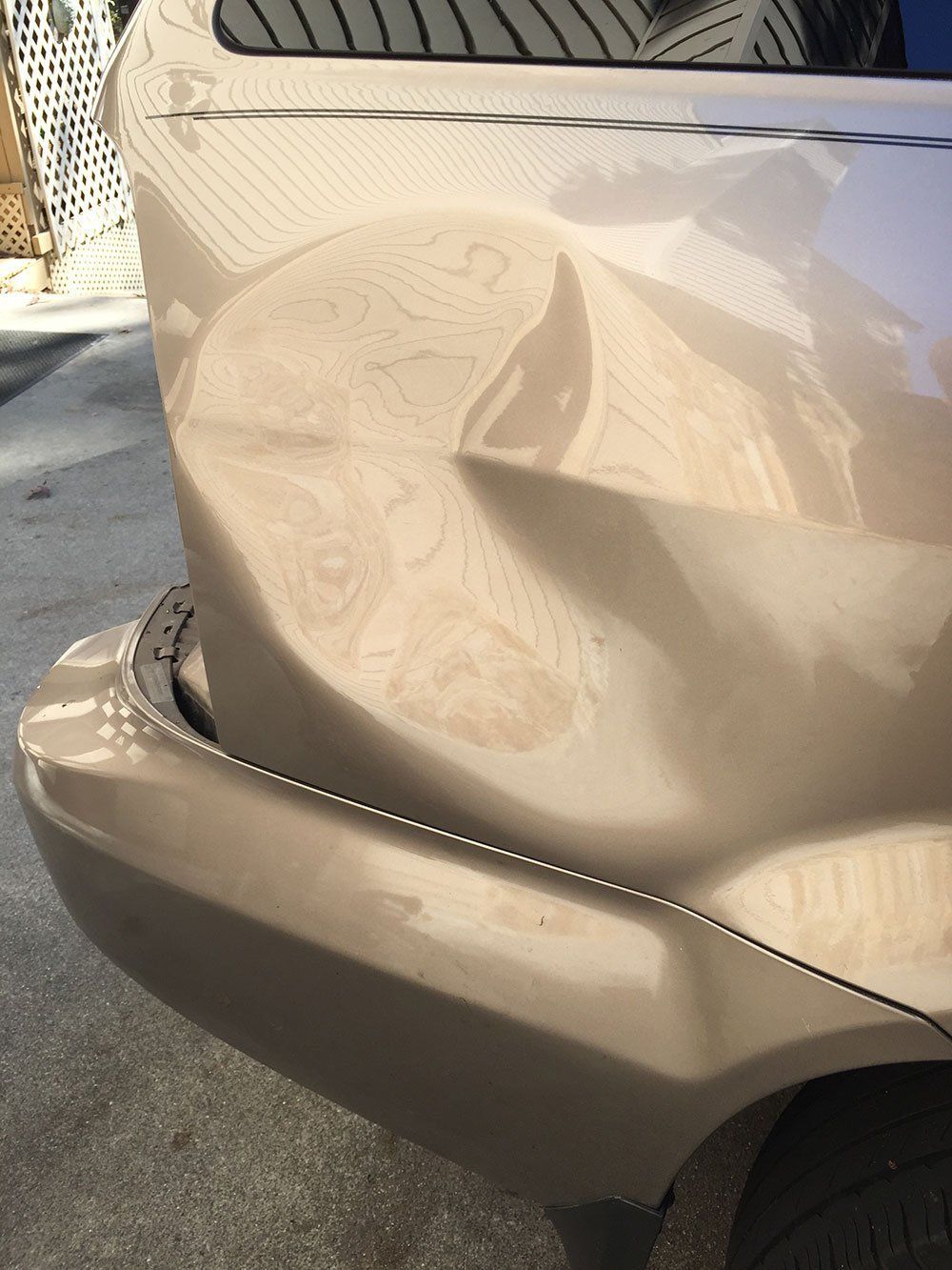 A car with a damaged bumper is parked on the side of the road.