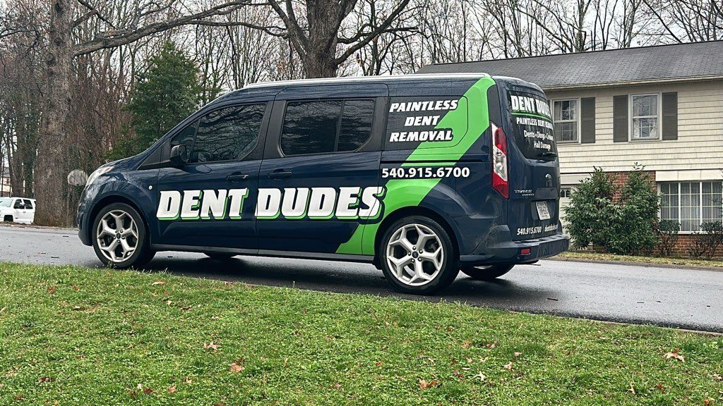 A white car with a damaged bumper is parked on the side of the road.
