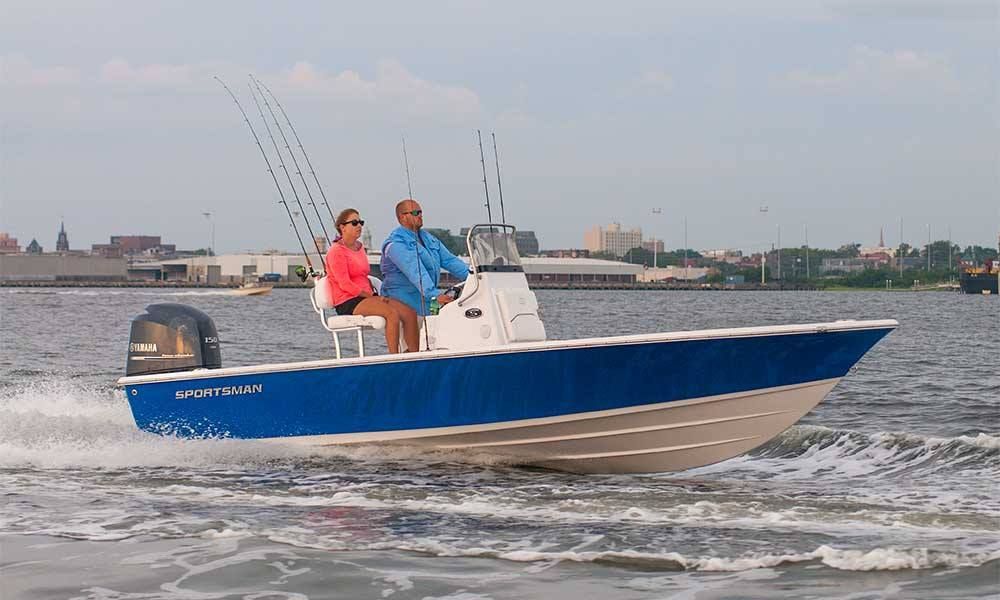 A man and a woman are riding a blue and white boat on the water.