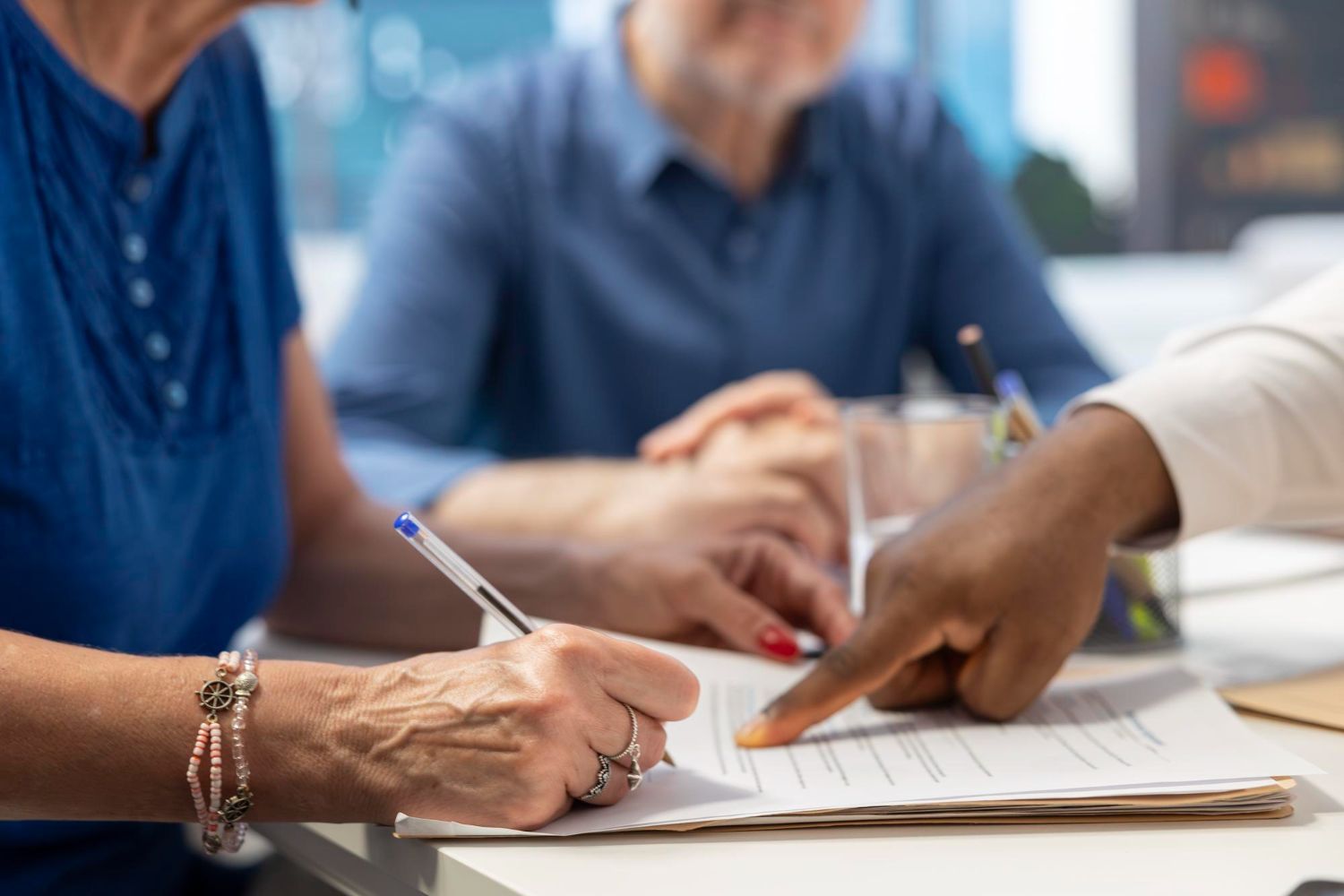 Hands writing and pointing at papers during a meeting at a table
