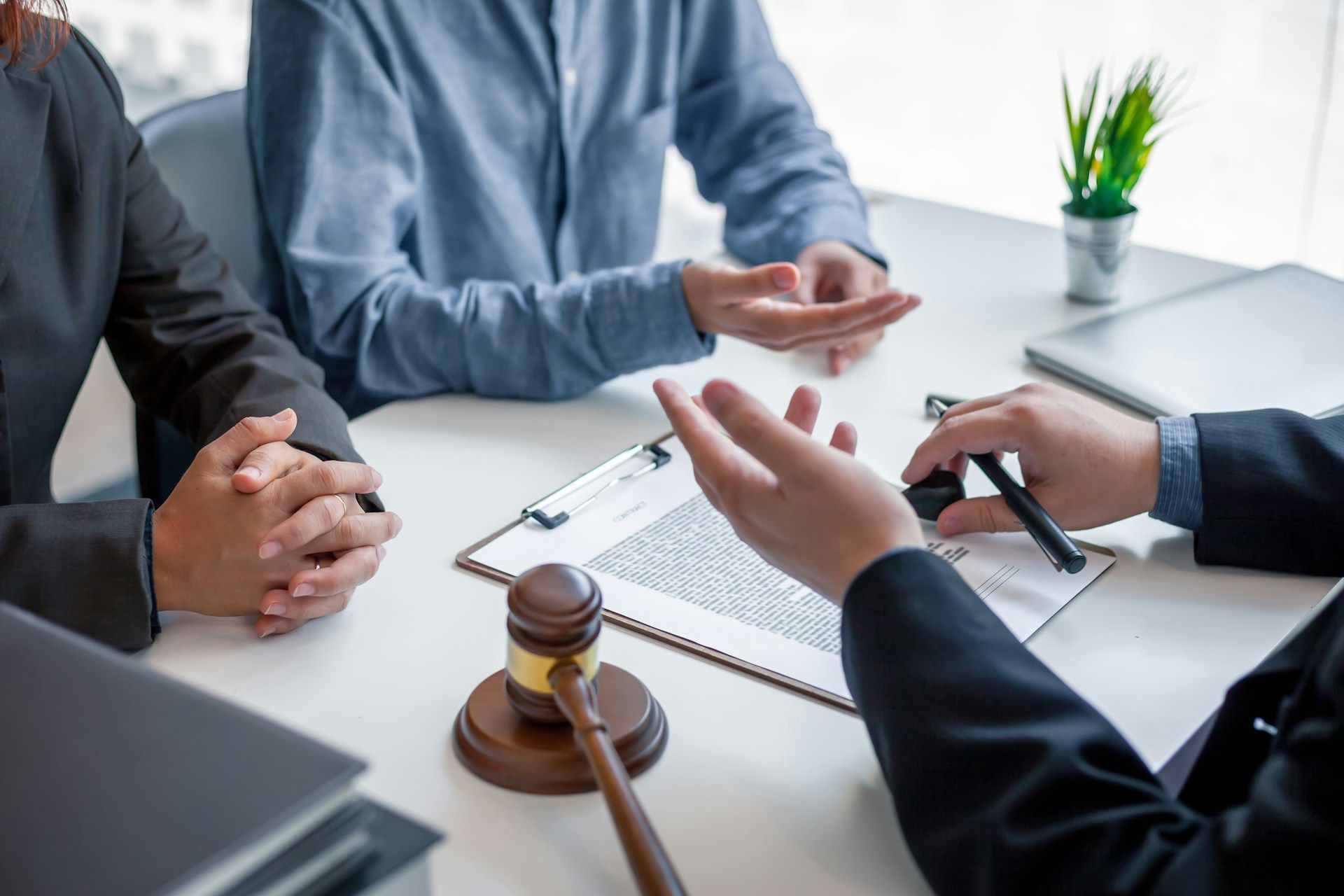 Legal professionals in a meeting with a client, with a gavel on a table holding a document.