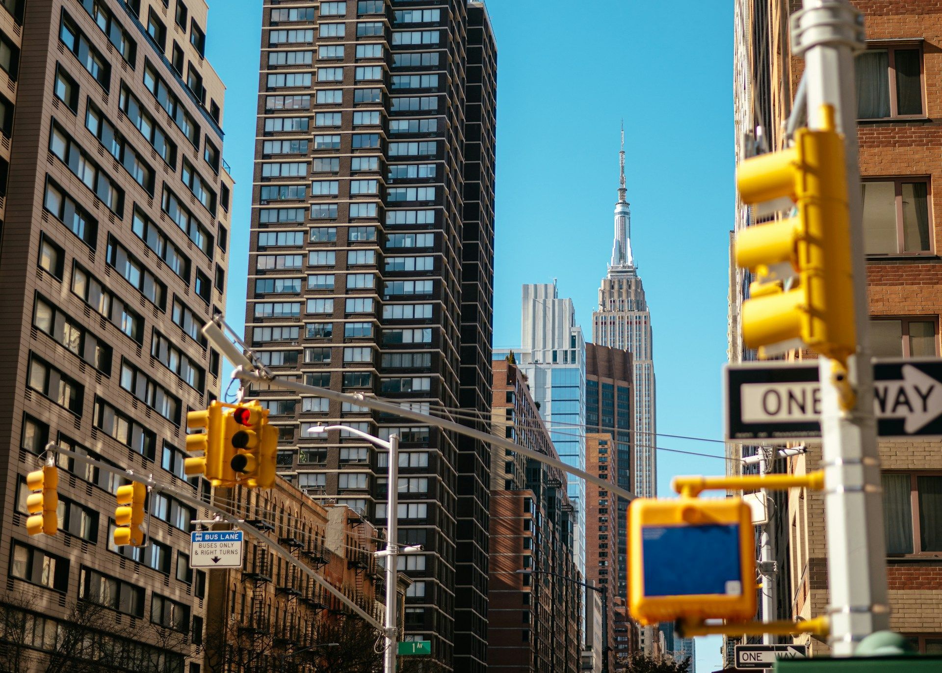 Looking up at city skyscrapers, including the Empire State Building, with traffic lights in the foreground.