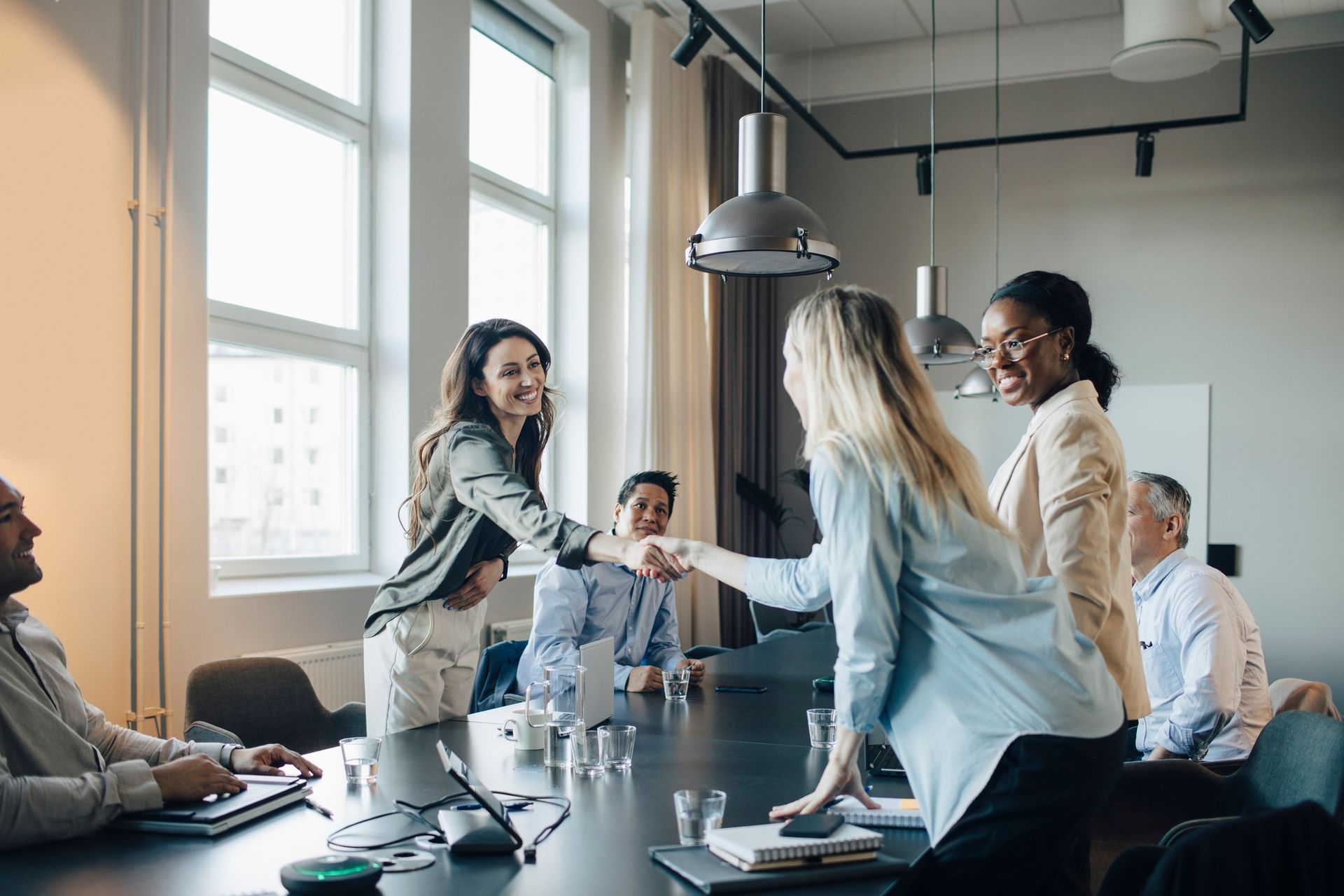 A group of people are shaking hands in a conference room.