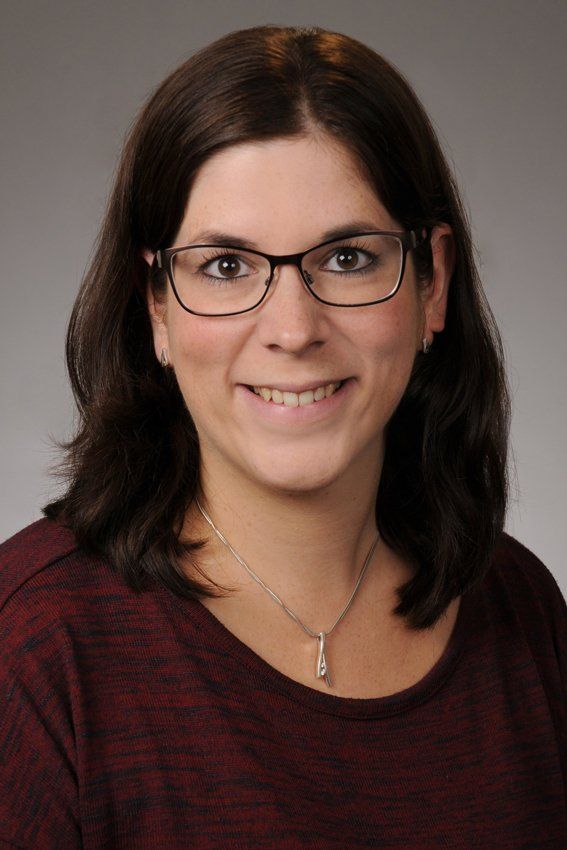 Eine Frau mit Brille und Halskette lächelt in die Kamera.