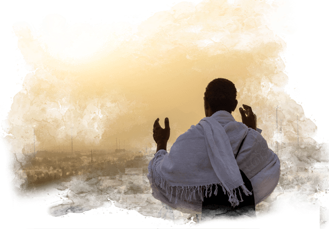 A man is sitting on the ground with his hands in the air and praying.
