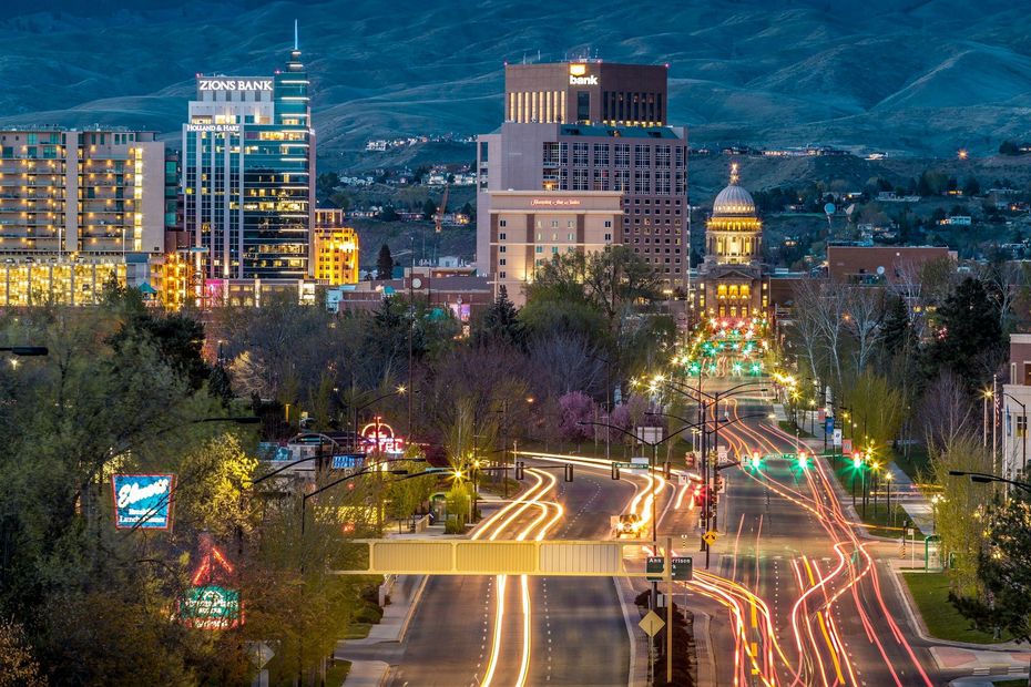 Downtown city skyline at dusk with illuminated streets and light trails from traffic