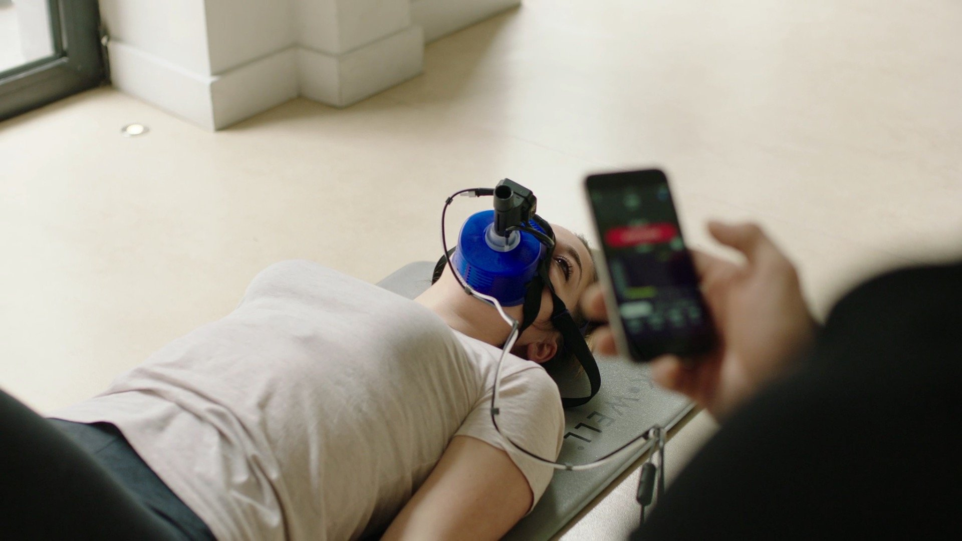 A man is laying on the floor with headphones on his head and a cell phone in his hand.