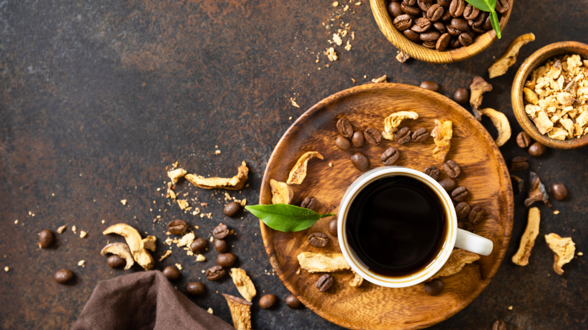 A cup of coffee is sitting on a wooden plate surrounded by coffee beans.