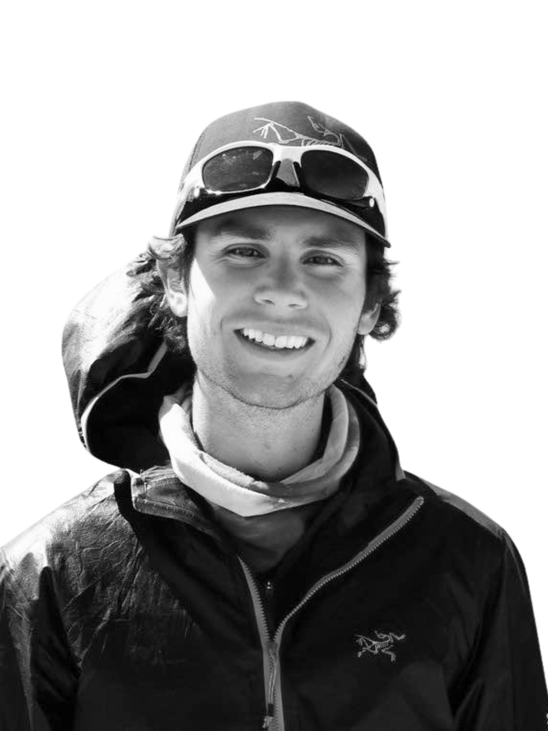 A man wearing a hat and sunglasses is smiling in a black and white photo