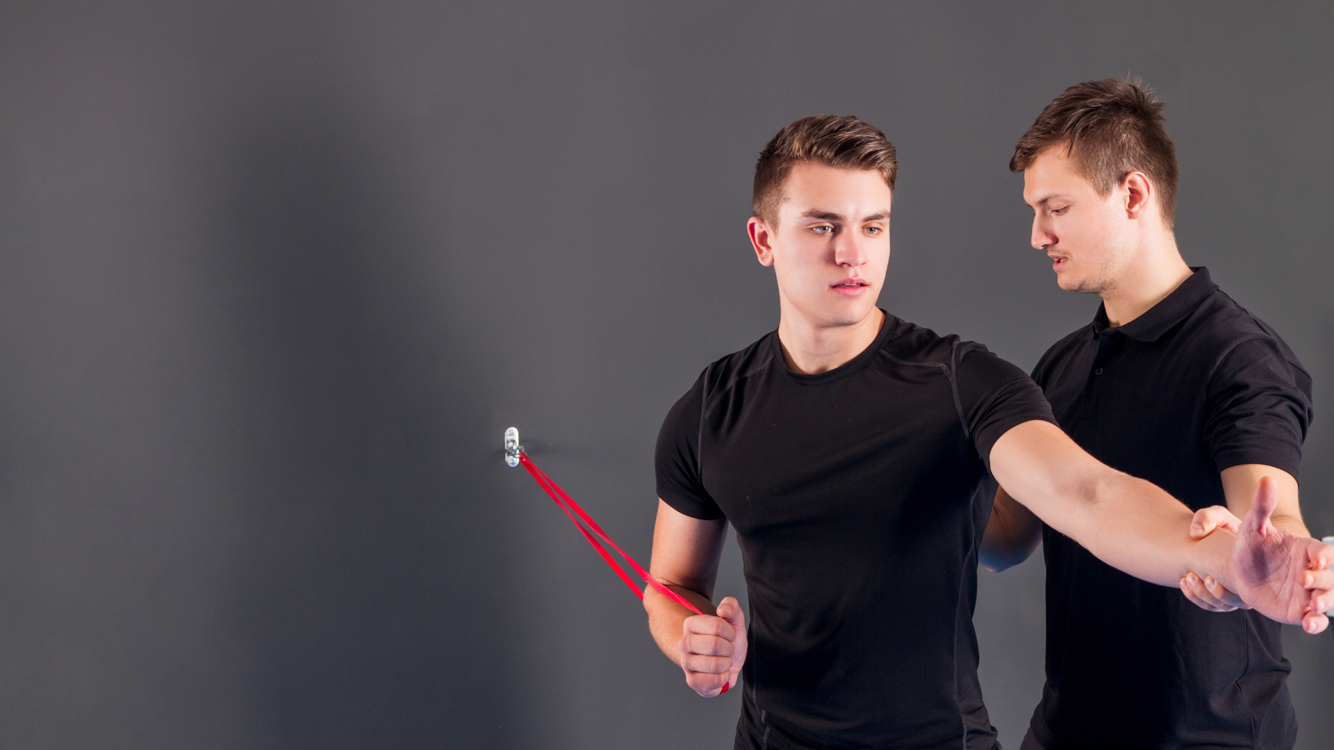 Two young men are doing exercises with a rubber band.