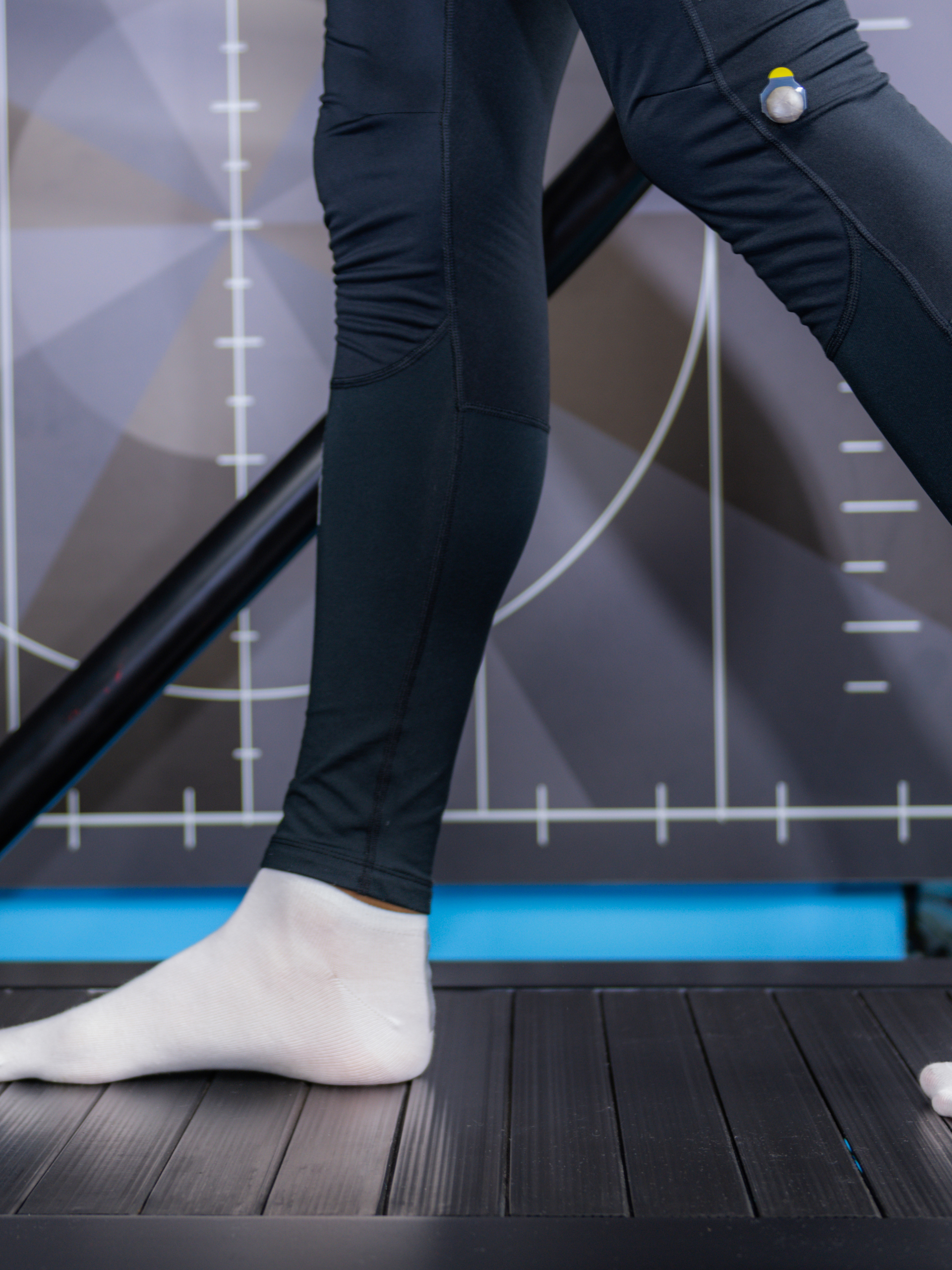 A person wearing black pants and white socks is walking on a treadmill