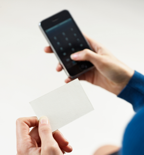 Person dialing phone number with a credit card in hand.