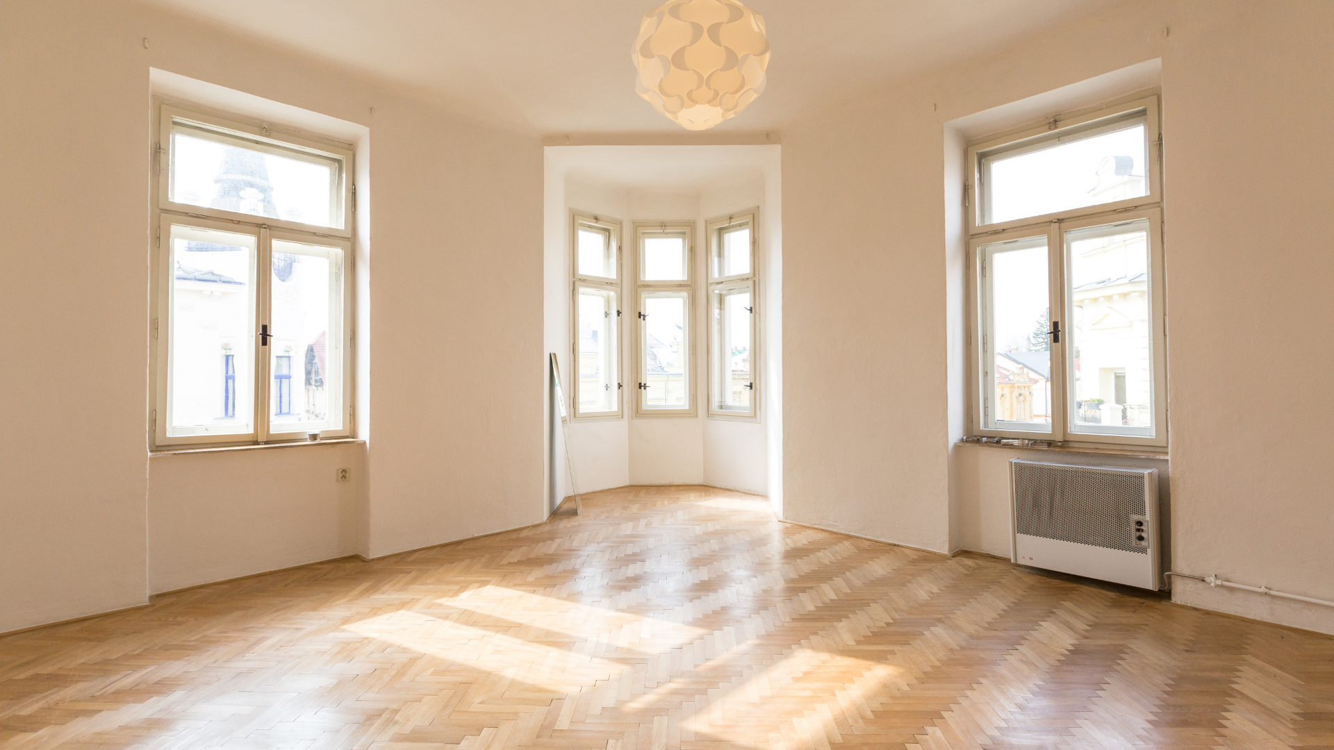 An empty living room with hardwood floors and lots of windows.