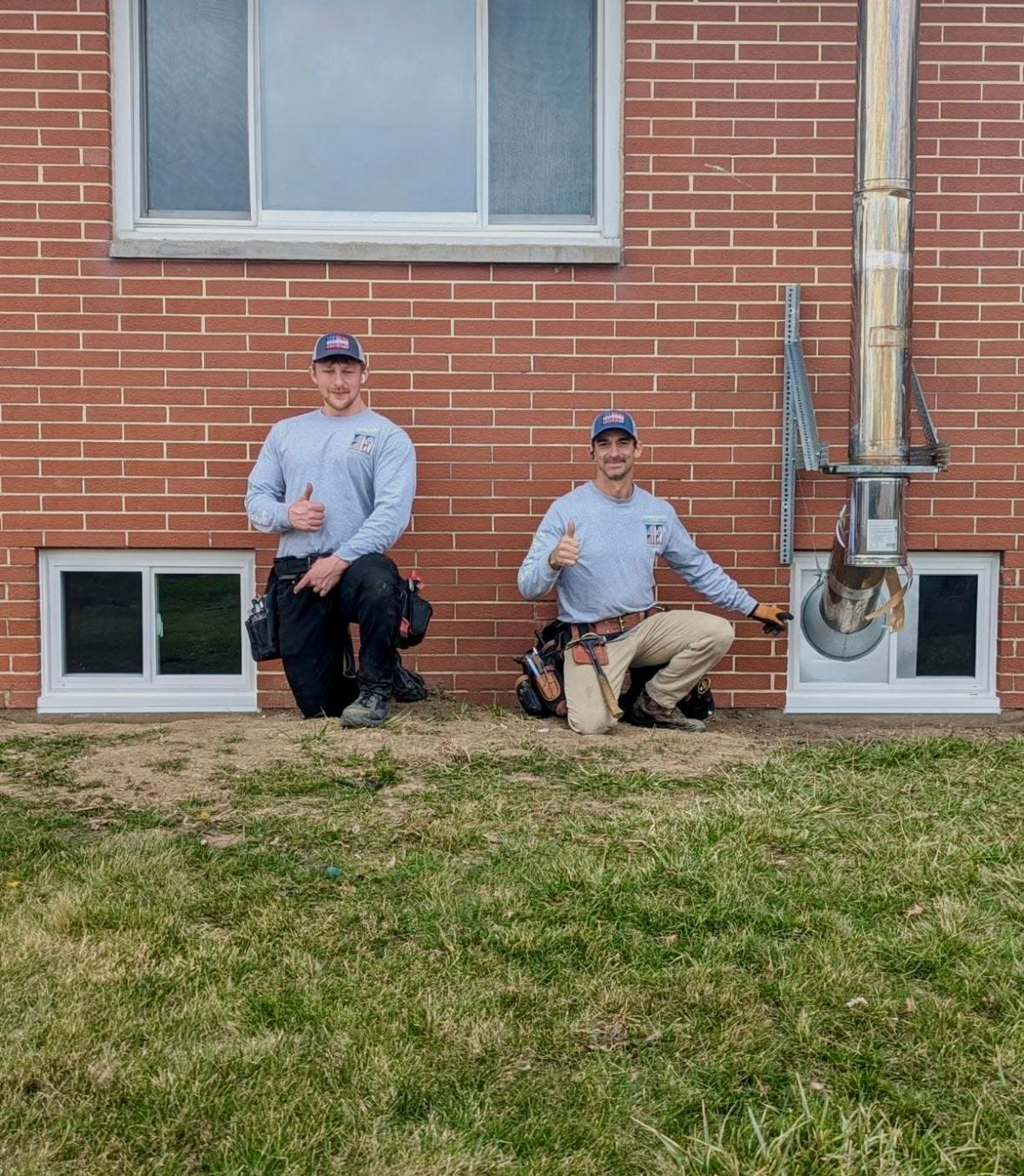 2 people standing outside a brick wall
