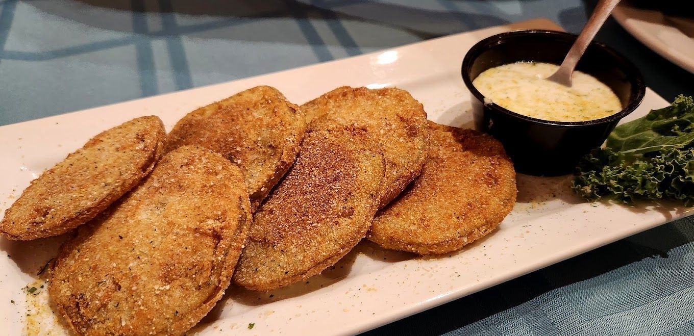 A white plate topped with fried pickles and a dipping sauce.