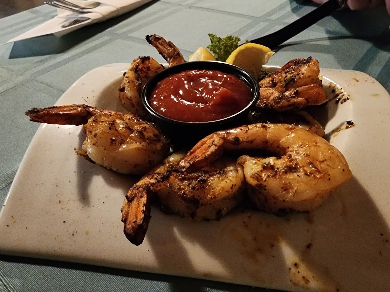 A plate of shrimp with a small bowl of ketchup