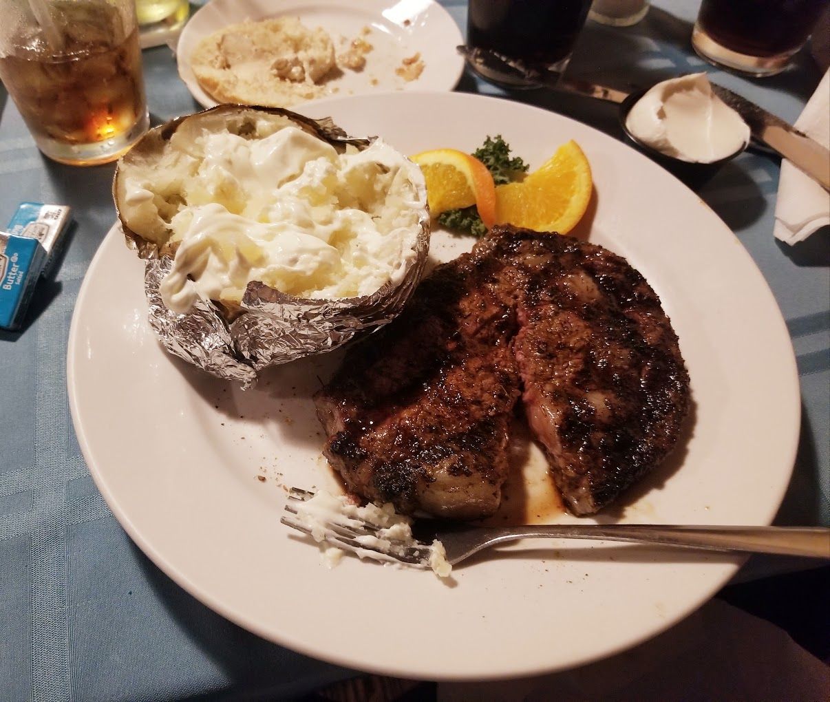 A white plate topped with a steak and a baked potato