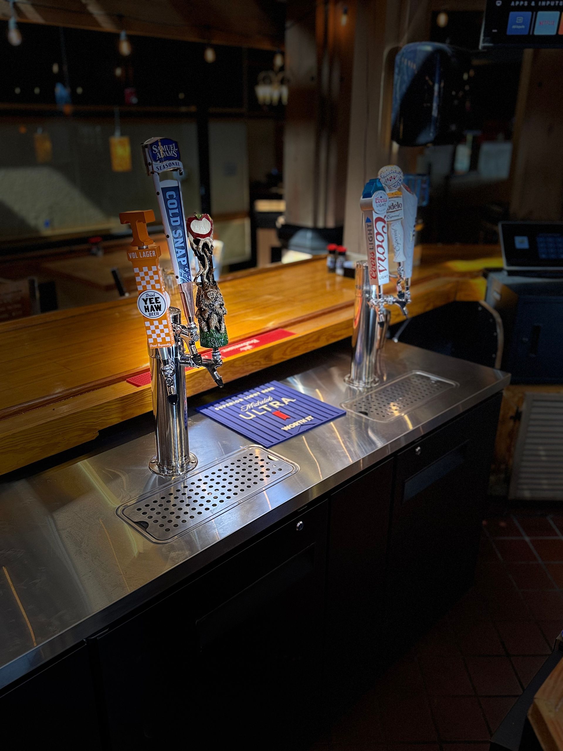 A bar with a stainless steel counter top and two beer taps.