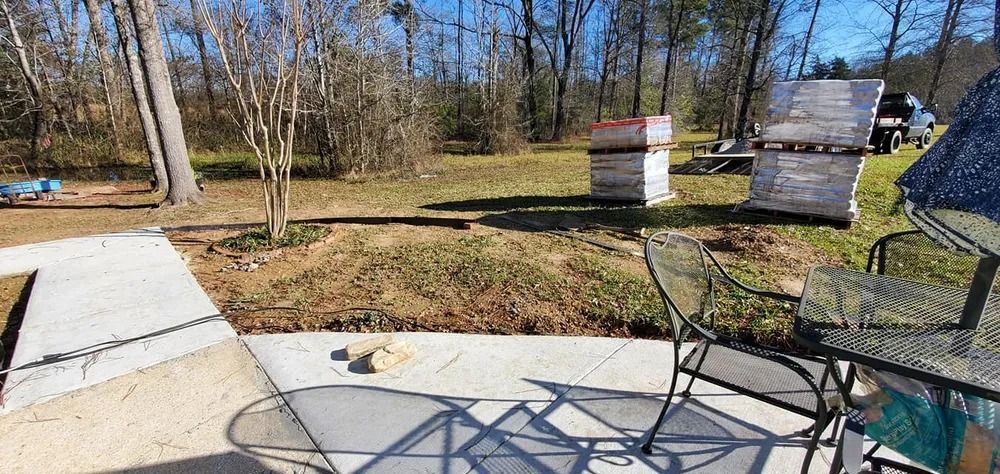 A sunny outdoor scene with stacks of materials in the background and a patio table in the foreground.