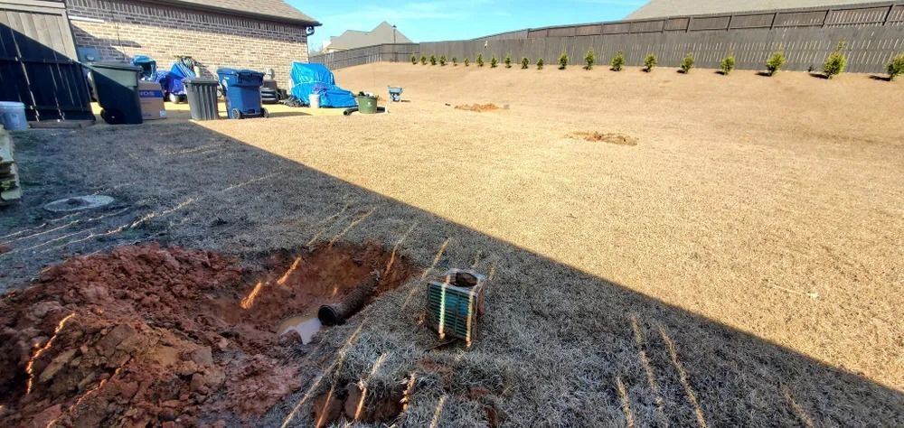 A yard with construction in progress. A pile of dirt and posts are in the foreground. A fence is in the background.