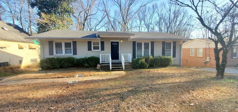 A one-story house with gray siding, blue shutters, and a black door.