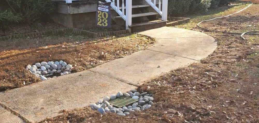 A concrete walkway leading to house steps with address 5023, bordered by landscaping rocks.