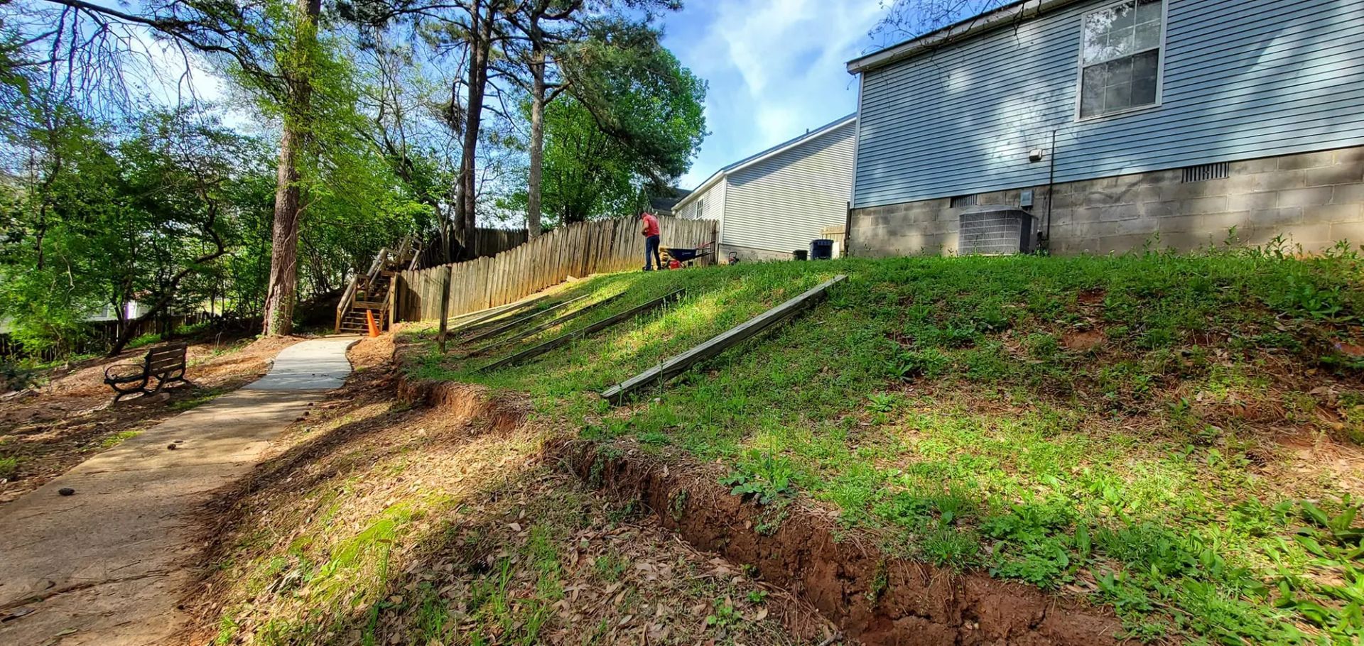 A grassy hillside with a pathway and a building in the background.