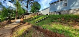 A grassy hillside with a pathway and a building in the background.