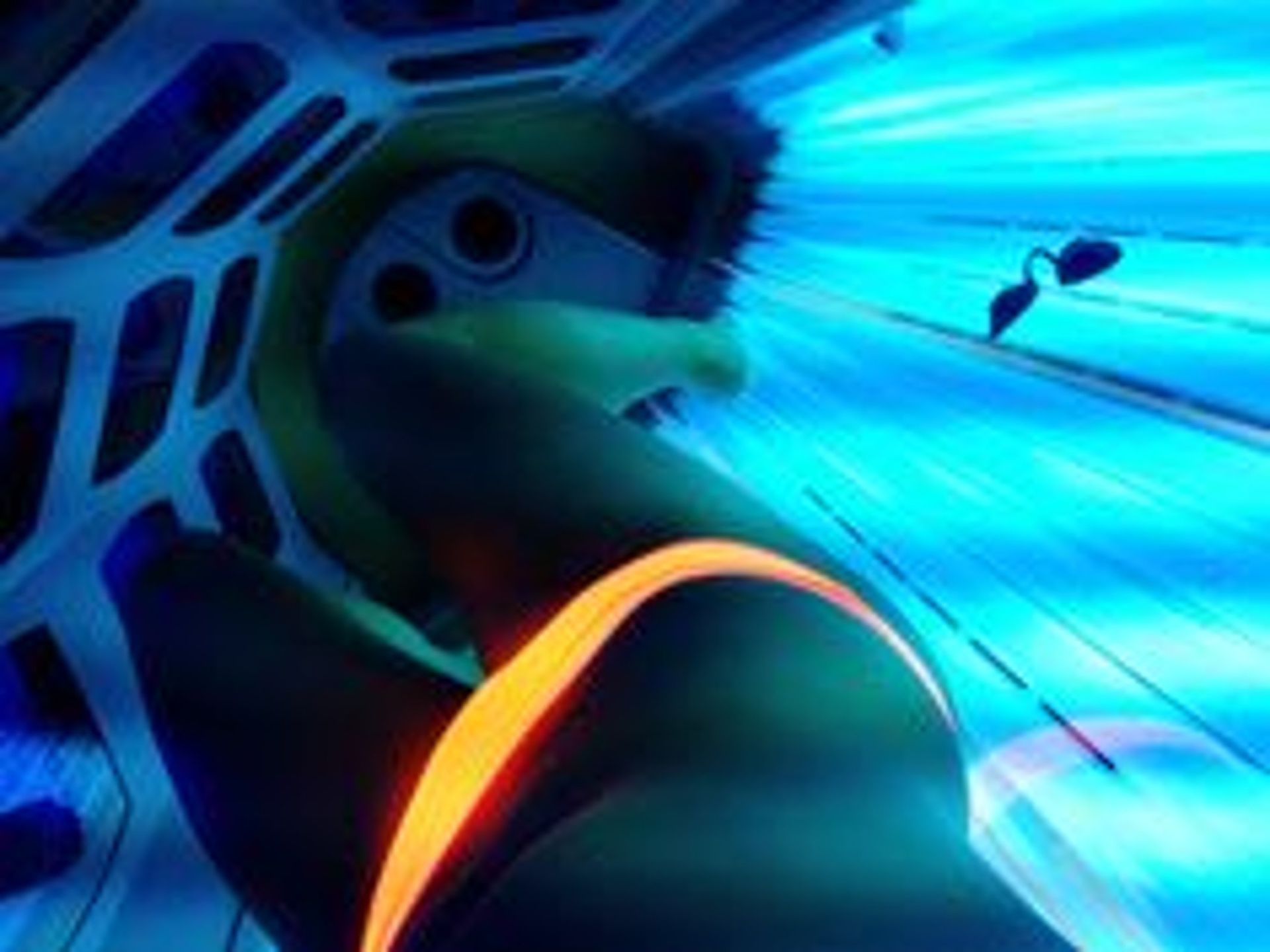Person's arm in tanning bed, under bright blue-orange light.