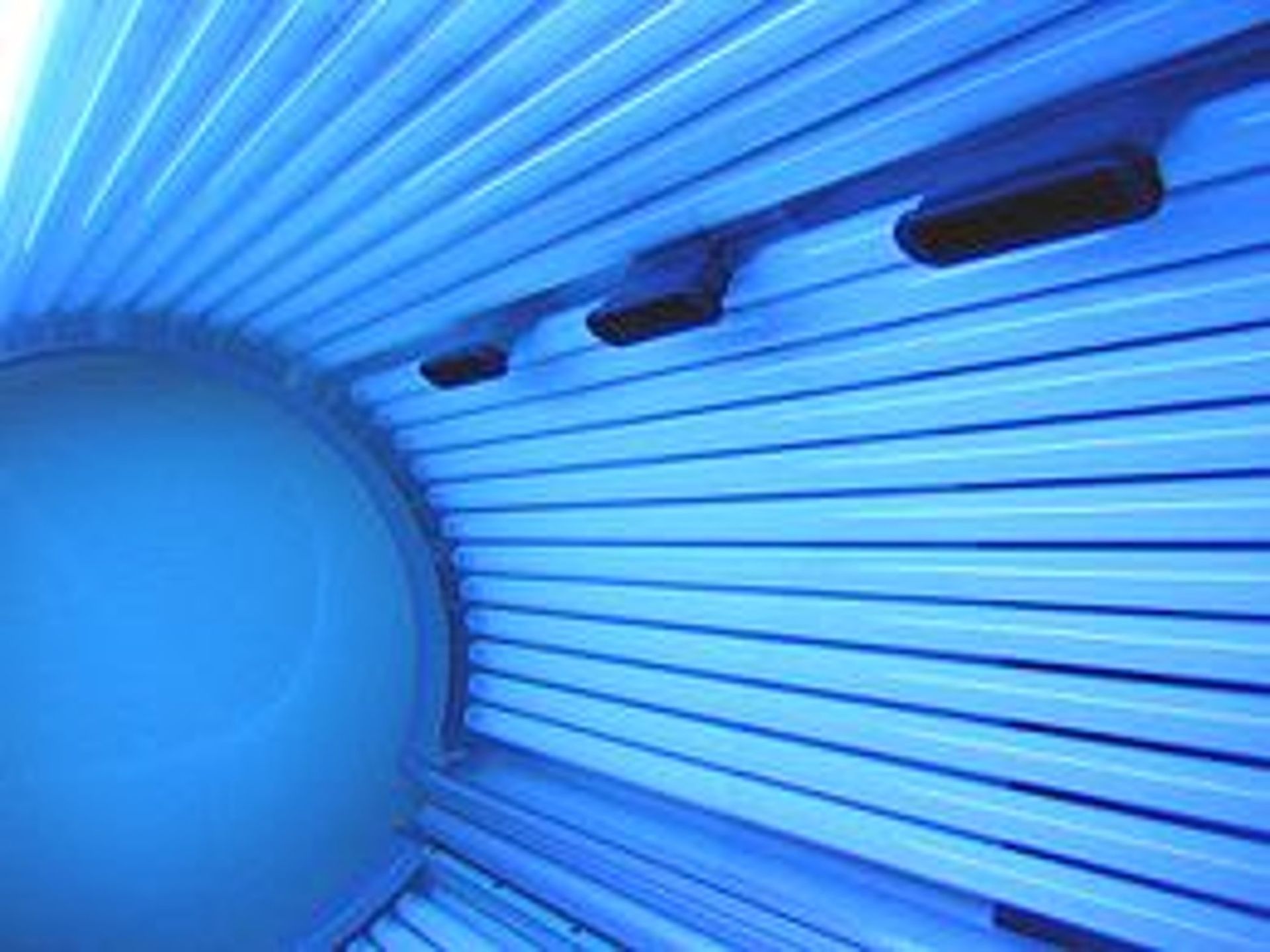 Interior of a tanning bed with blue UV lights.
