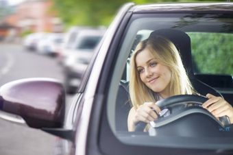 Smiling female checking the wing mirrors