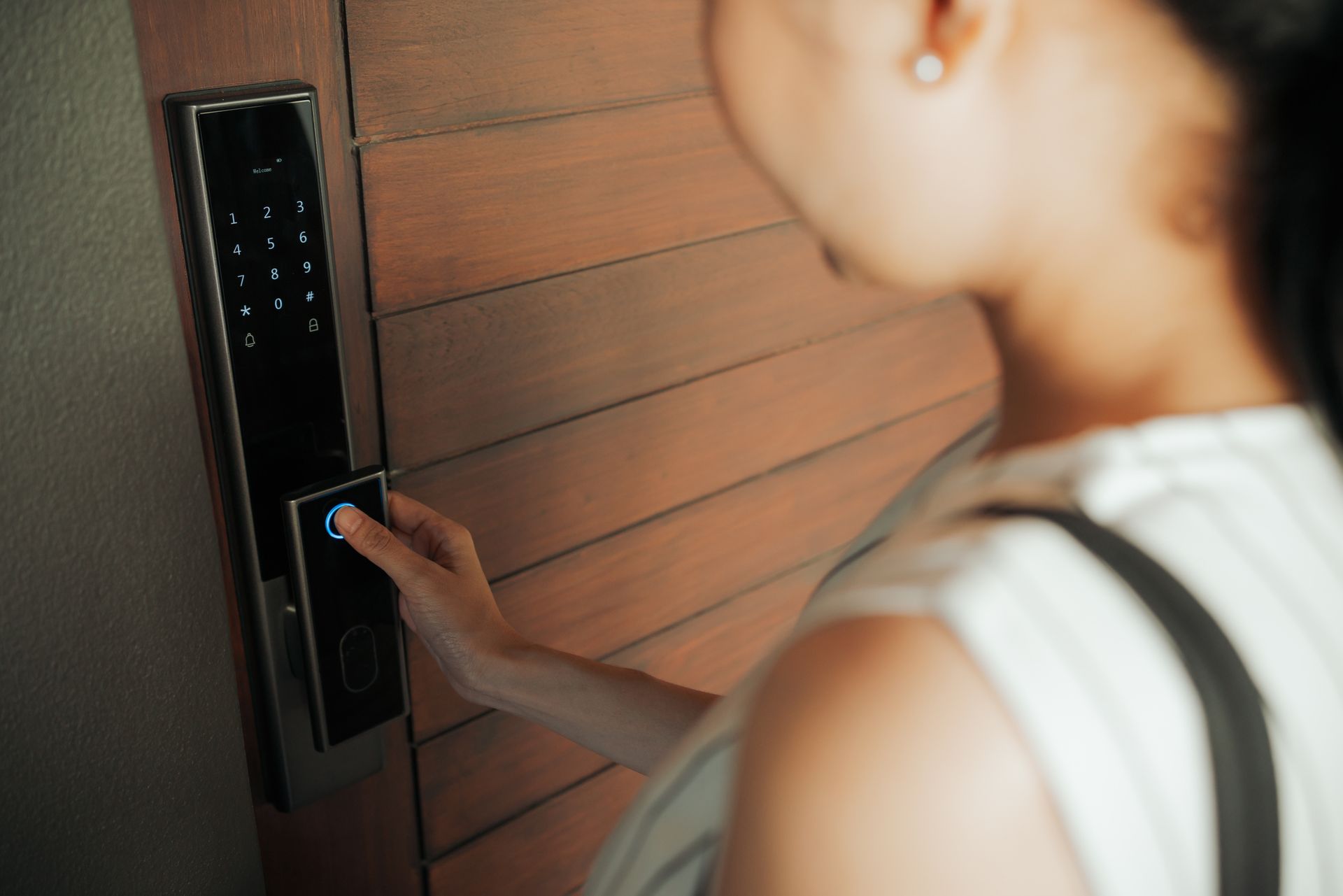 Close-up of a woman pressing an electronic door panel, showcasing gated access control in action.