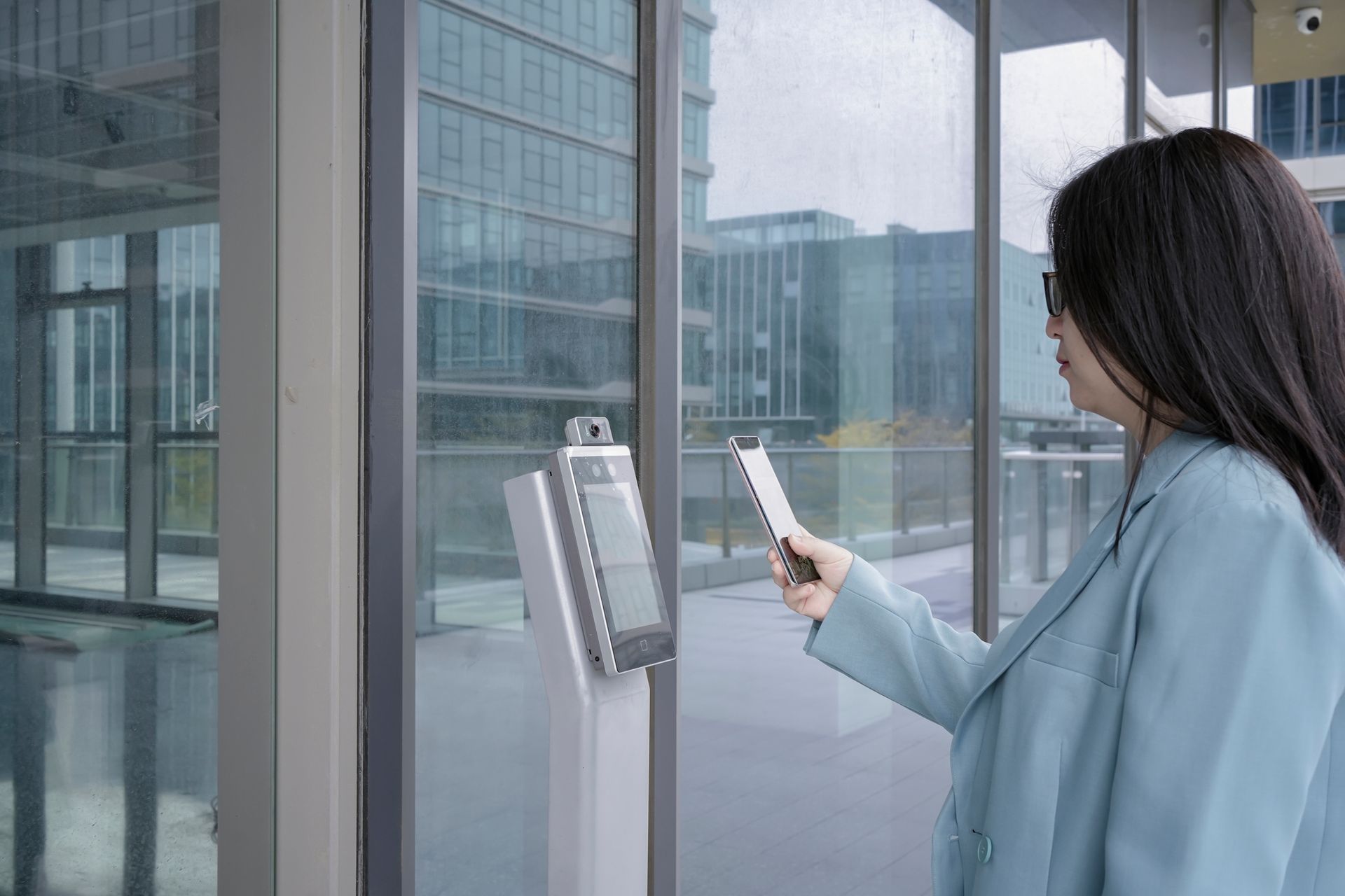 Picture of a woman using an electronic access control system to enter a building Picture of a woman using an electronic access control system to enter a building