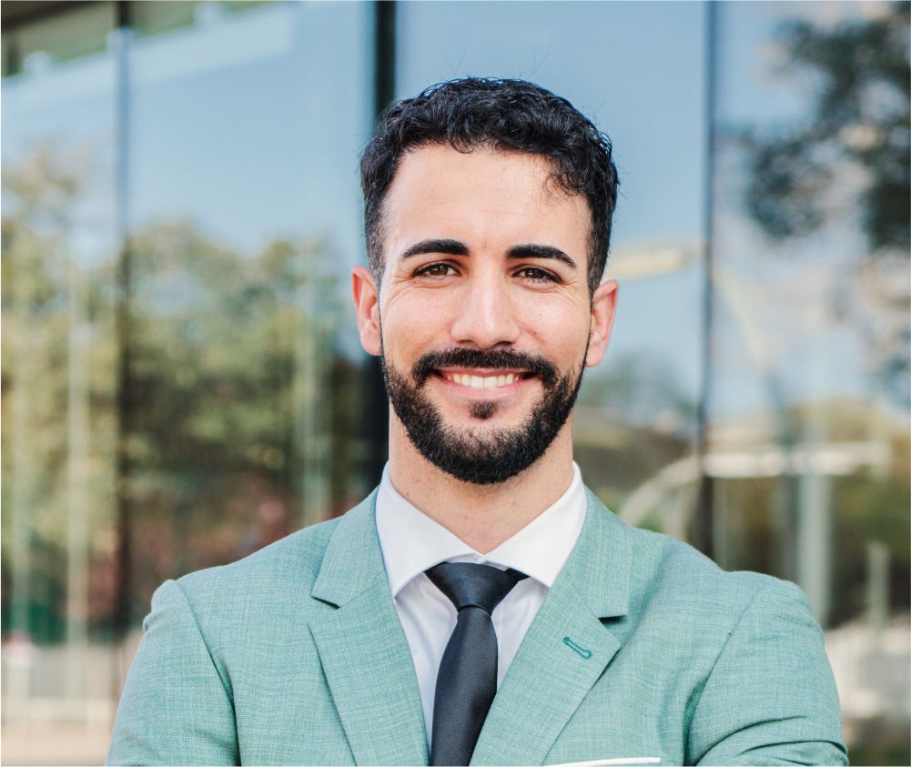 A man with a beard is wearing a green suit and tie.