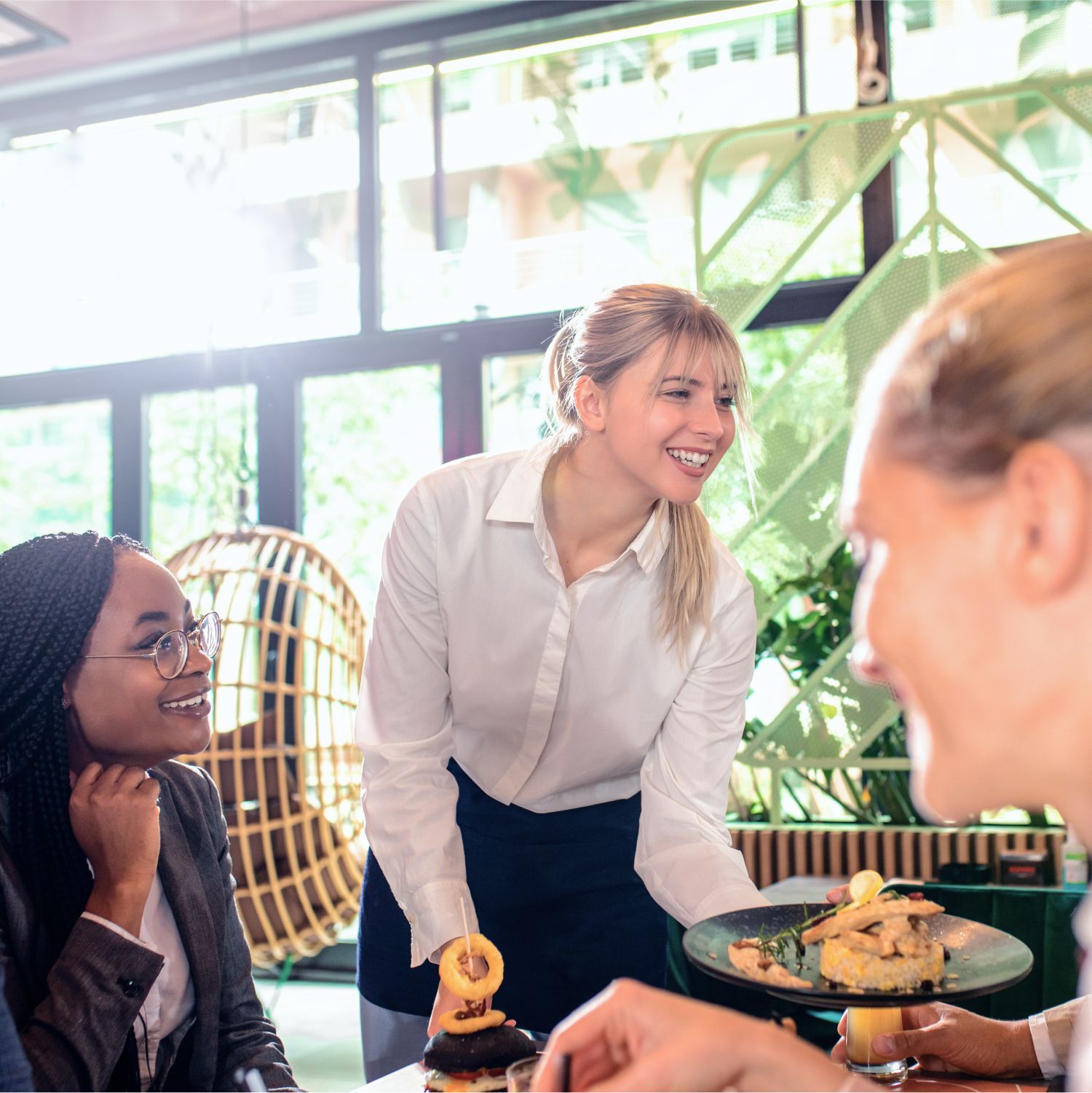 A woman is serving food to a group of people at a table.