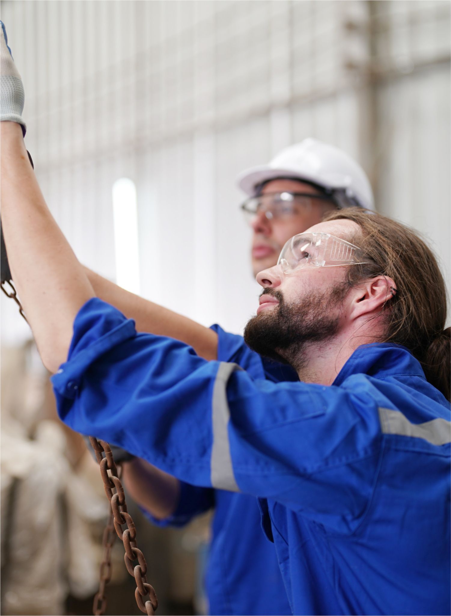 Two men are working on a chain in a factory.