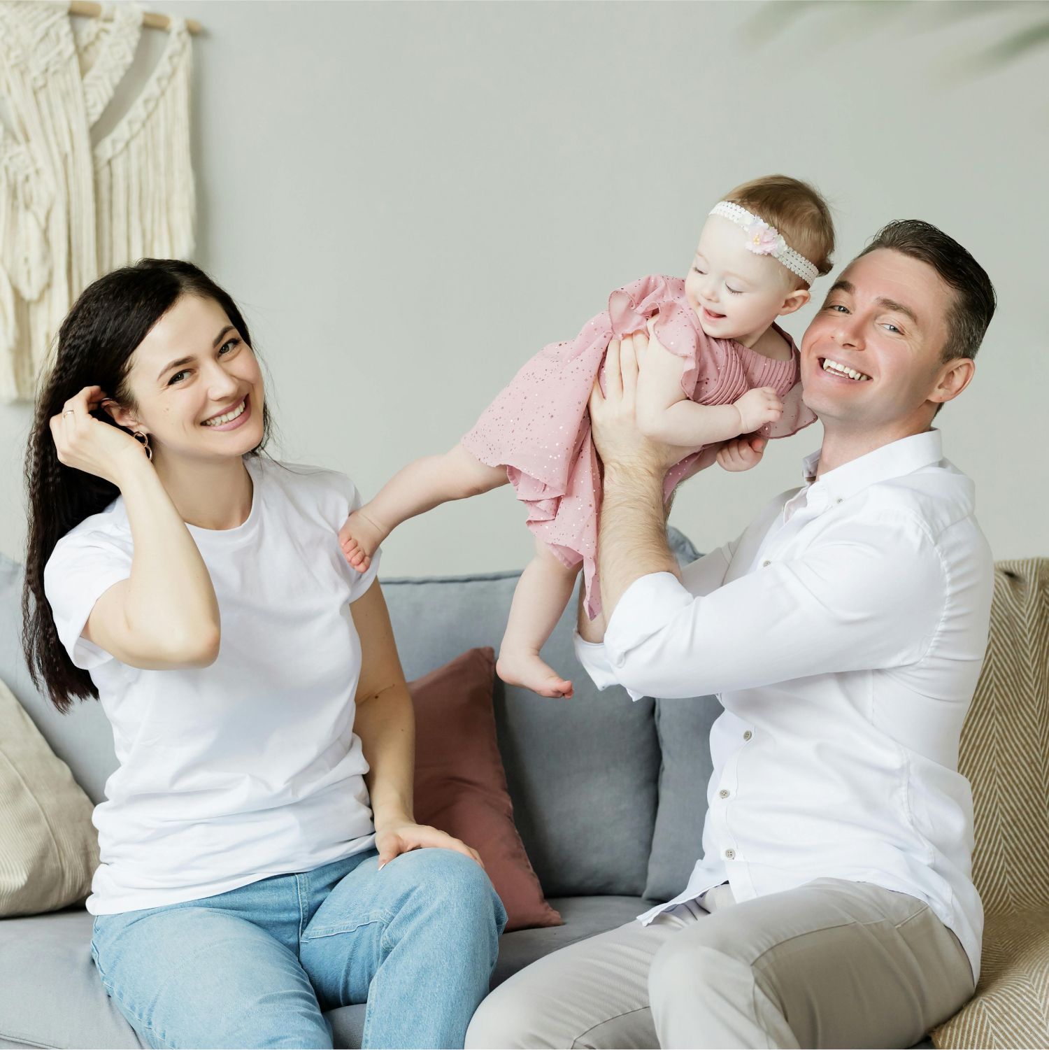 A man and a woman are sitting on a couch holding a baby.