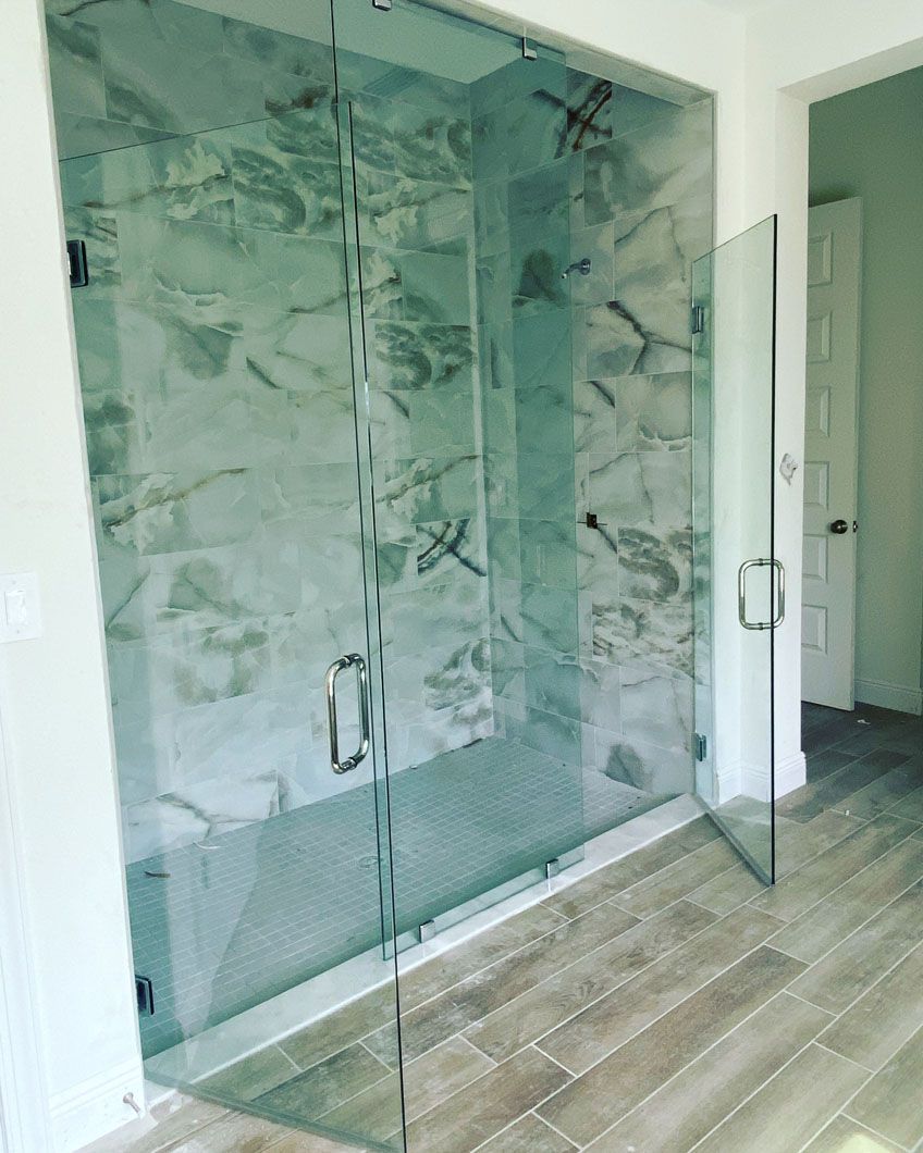 A bathroom with a walk in shower and a glass door.