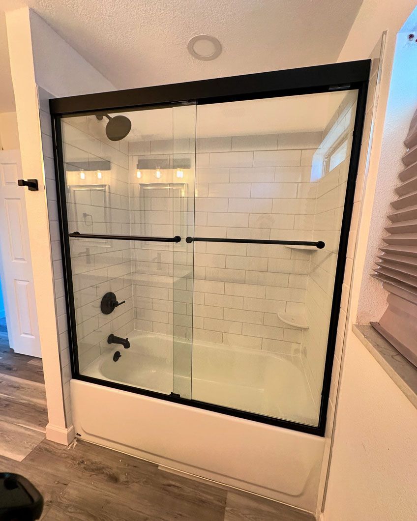 A bathroom with a sliding glass shower door and a bathtub.